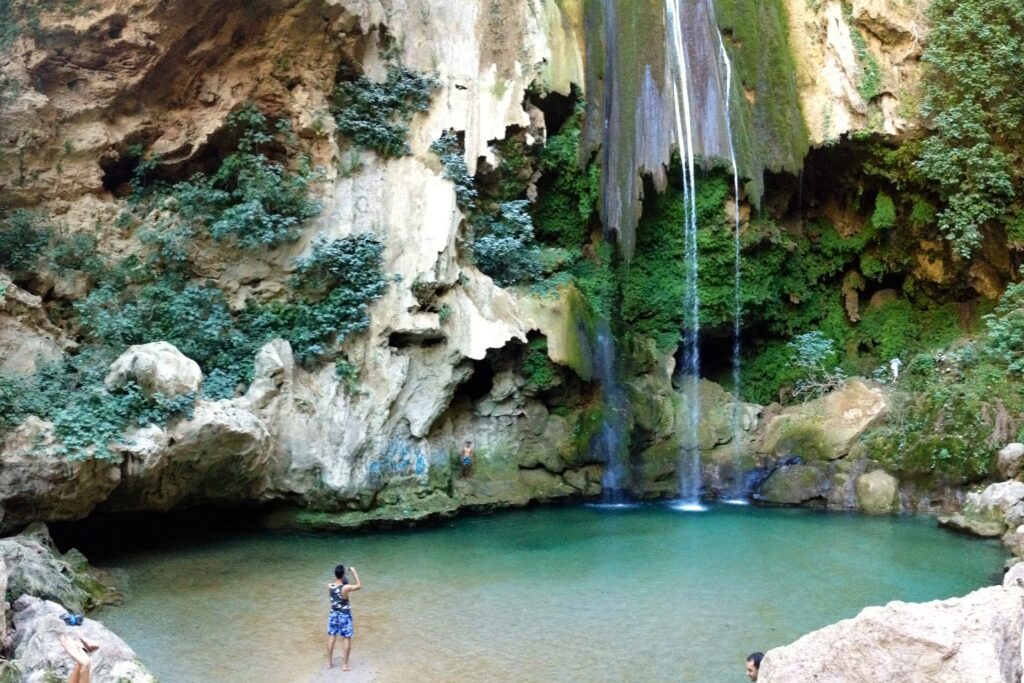 Mulher com os pés nas águas do lago formado pelas Cascatas de Akchour, distante 30 km de Chefchaouen. No entorno paredões das formações geológicas, de onde vem as águas das Cascatas.