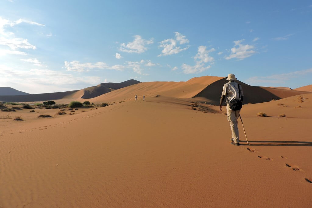 Pessoa praticando caminhada de aventura nas dunas do deserto na Namíbia.