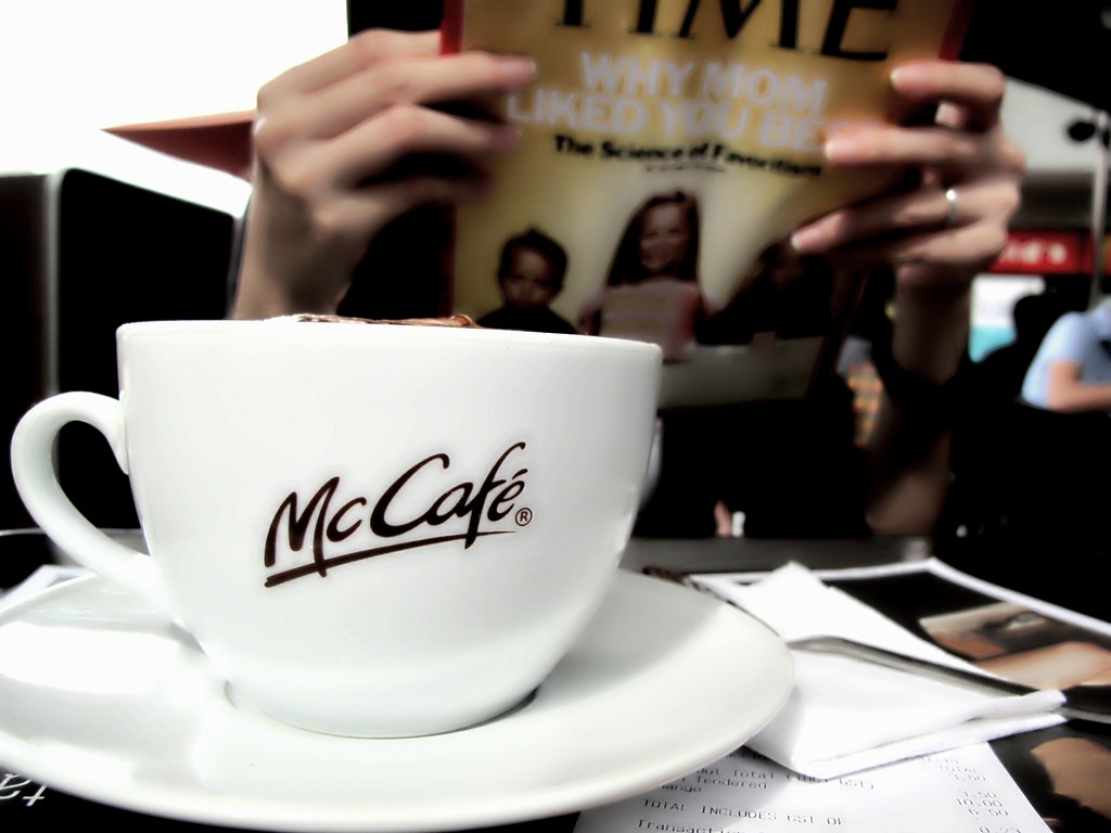 Pessoa lendo uma revista Times enquanto toma um café, é uma das maneiras de curtir o tempo quando Viajar sozinho