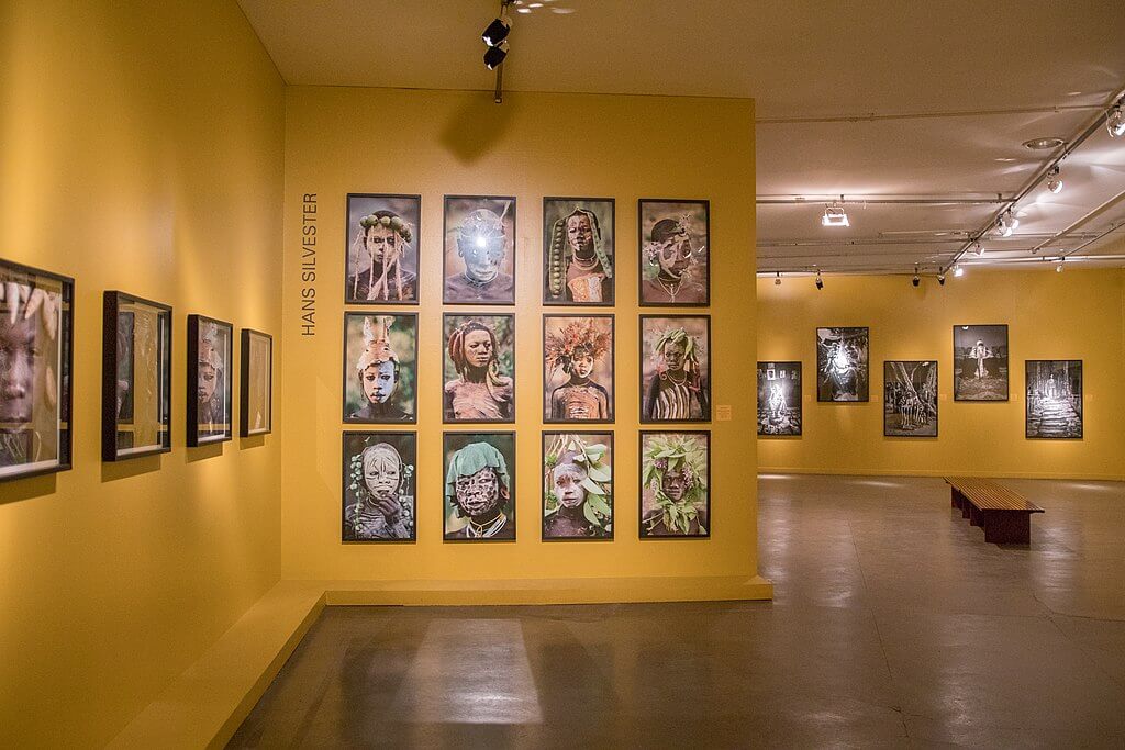 21 quadros de afro descendentes colocados em parede laranja do Museu Afro Brasil, um destino cultural de afroturismo.