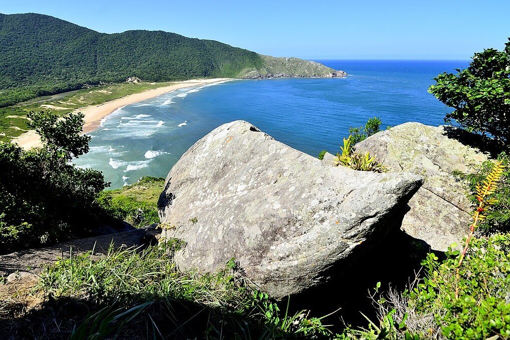 Rochas, vegetação, céu azul e o mar da Praia da Lagoinha do Leste, em Florianópolis. Um dos destinos dos mochileiros em SC.