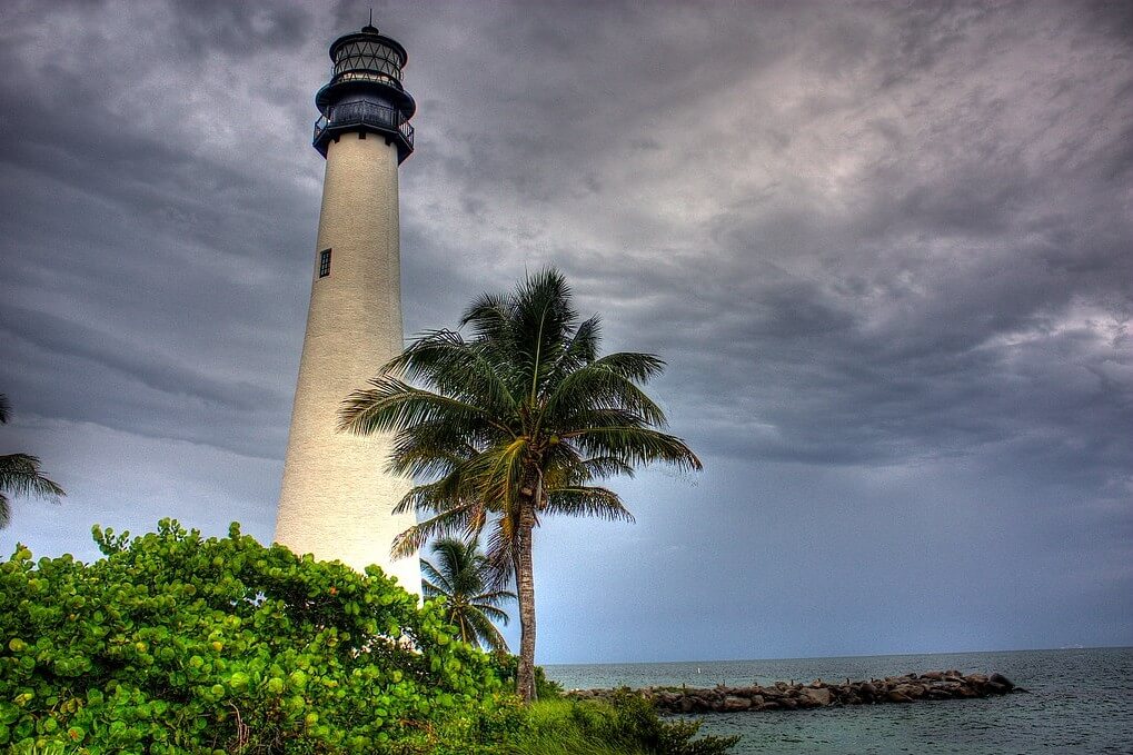 Céu nublado, fotografia em HDR do Cape Florida Lighthouse, palmeira e vegetação litorânea, o farol é um dos destaques de Key Biscane, imprescindível em um Roteiro de 7 Dias em Miami