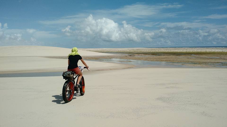 Pessoa de bicicleta realizando passeio de bicicleta no campo de dunas do Parque Nacional dos Lençóis Maranhenses. Segmentos como o turismo de aventura e o turismo gastronômico têm mostrado um crescimento significativo na gestão de mídias sociais no turismo.